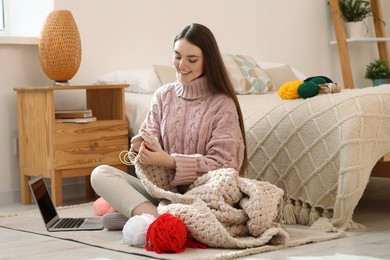 Woman learning to knit with online course at home. Handicraft hobby
