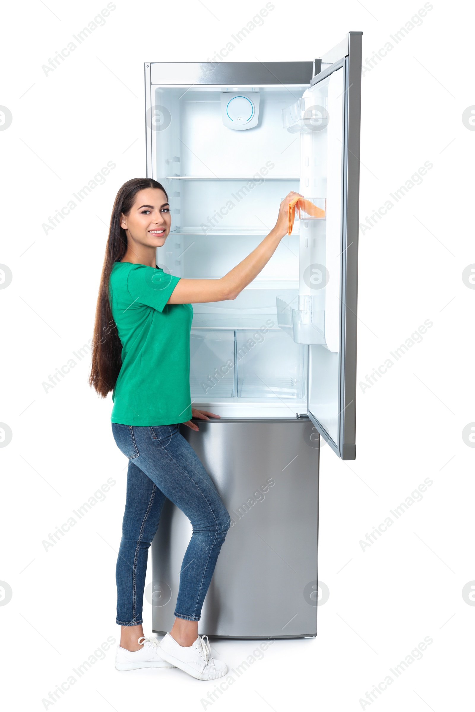 Photo of Young woman cleaning refrigerator with rag on white background