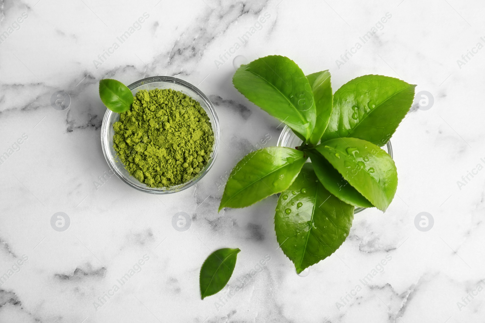 Photo of Bowl with matcha tea and green leaves on marble table, top view