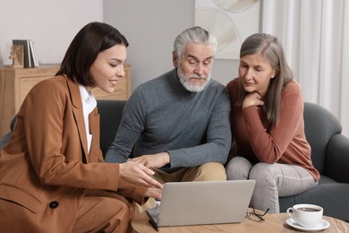 Insurance agent consulting elderly couple about pension plan in room