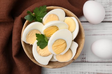 Photo of Fresh hard boiled eggs and parsley on white wooden table, flat lay