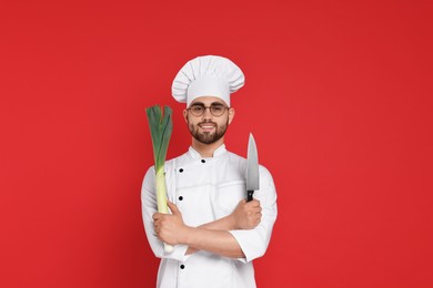 Professional chef with leek and knife having fun on red background