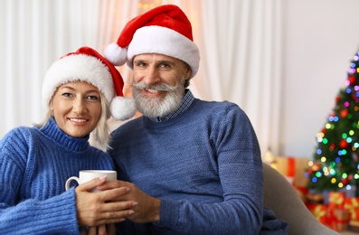 Happy couple in Santa hats celebrating Christmas at home