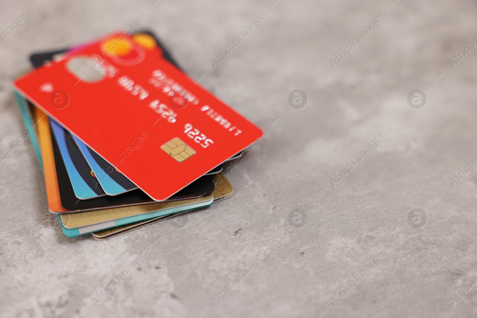 Photo of Pile of different credit cards on grey table, closeup. Space for text