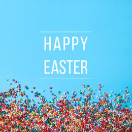 Image of Text Happy Easter and colorful sprinkles on light blue background, flat lay. Confectionery decor