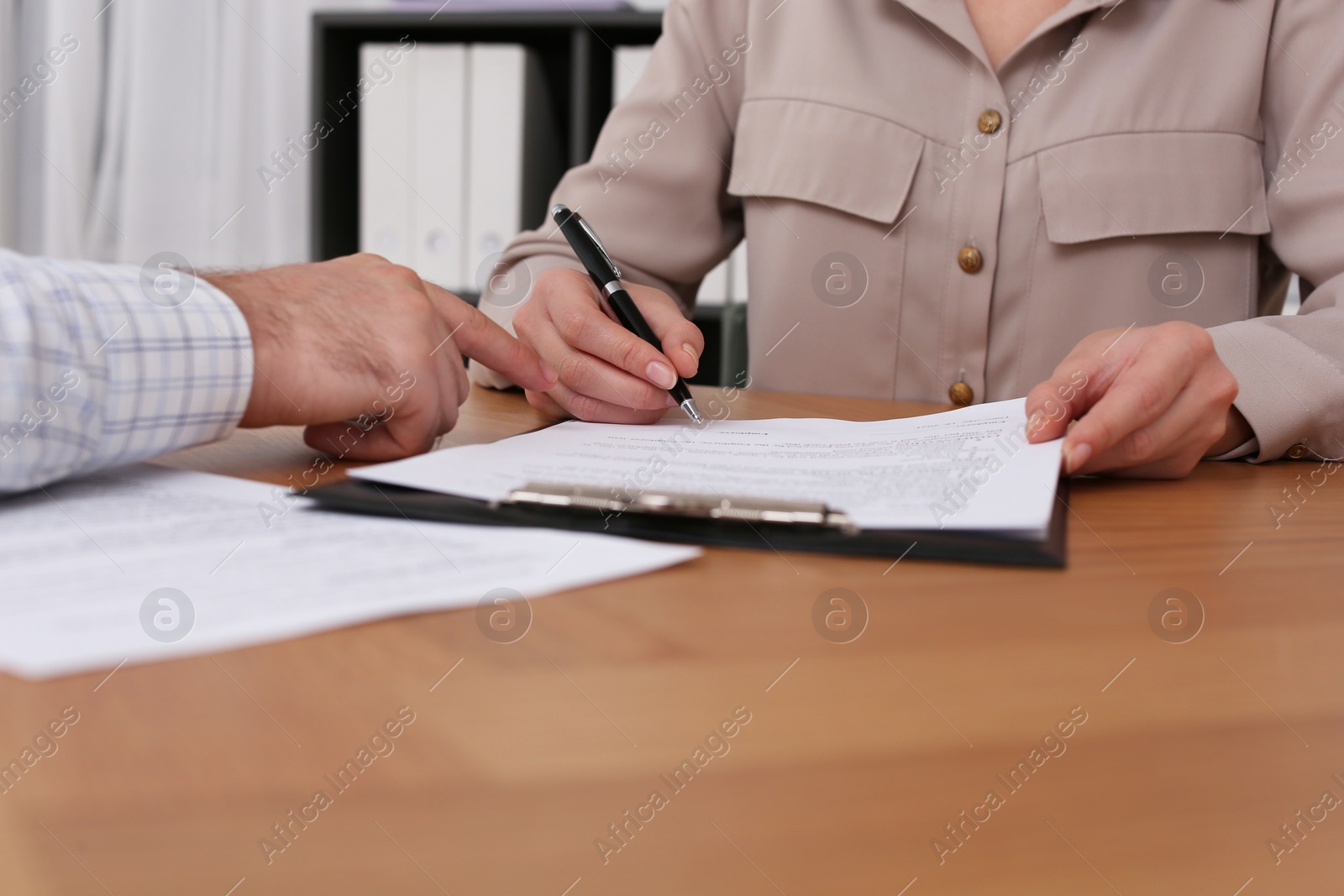 Photo of Businesspeople signing contract at wooden table indoors, closeup of hands