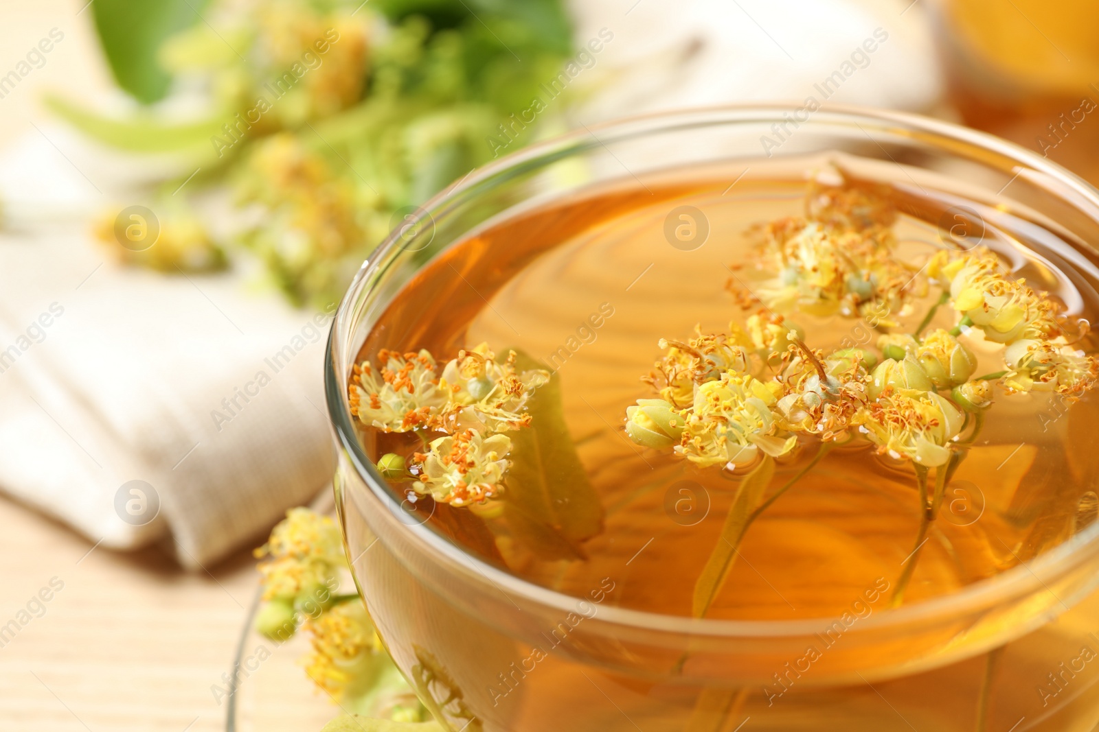 Photo of Cup of tea with linden blossom on table, closeup
