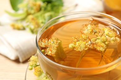 Cup of tea with linden blossom on table, closeup