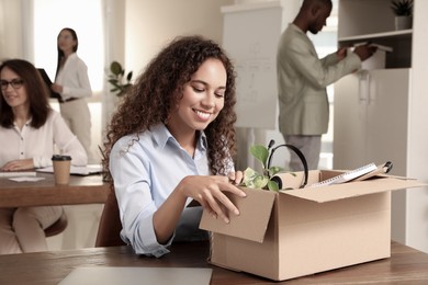 Photo of New coworker unpacking box with personal items at workplace in office