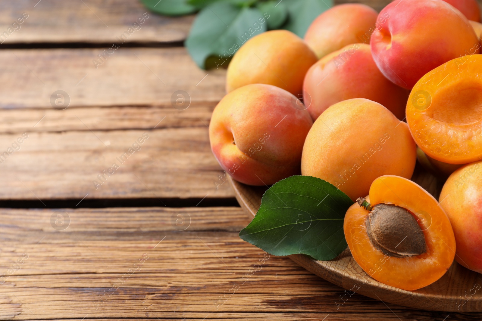 Photo of Delicious fresh ripe apricots on wooden table, closeup. Space for text