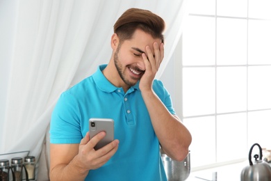 Young man laughing while using smartphone at home