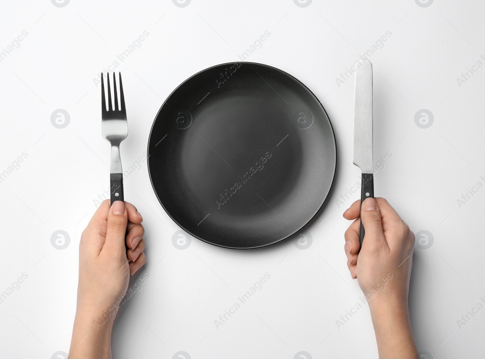 Photo of Woman with fork, knife and empty plate on white background, top view