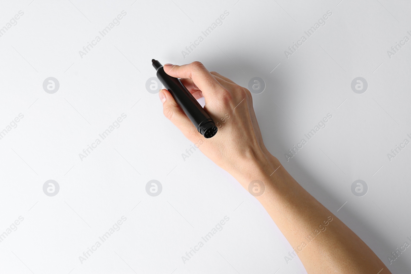 Photo of Woman holding black marker on white background, top view. Space for text