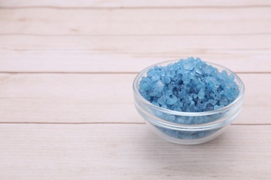 Photo of Bowl with blue sea salt on white wooden table. Space for text