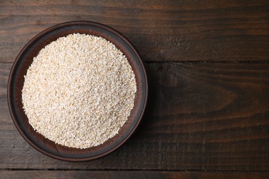 Raw barley groats in bowl on wooden table, top view. Space for text