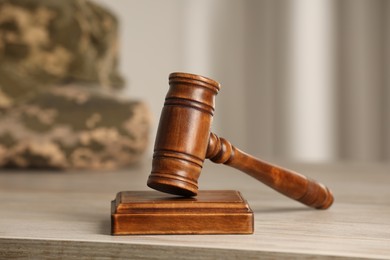 Photo of Law concept. Gavel and military uniform on wooden table, closeup