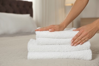 Photo of Chambermaid putting fresh towels on bed in hotel room, closeup. Space for text