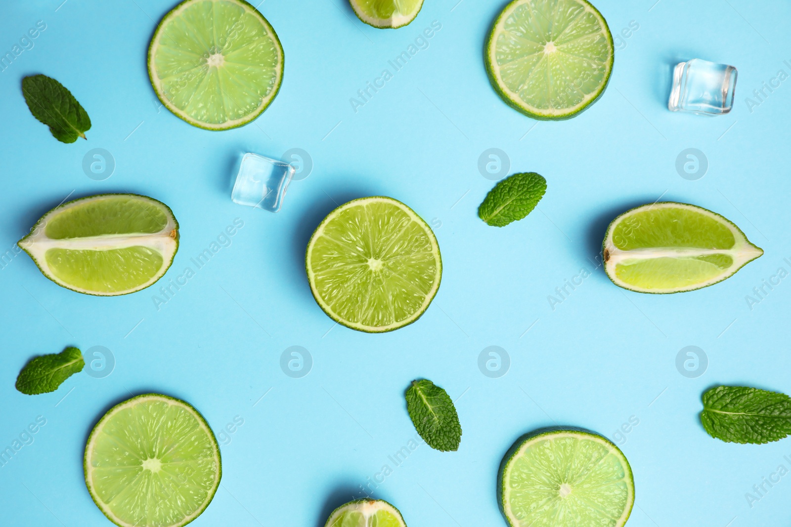 Photo of Flat lay composition with fresh juicy limes, mint and ice cubes on light blue background