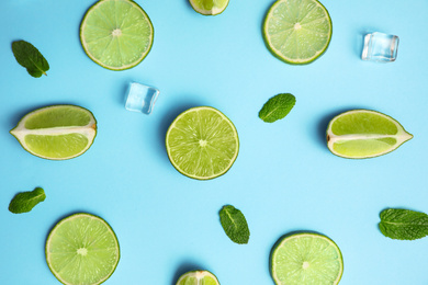 Flat lay composition with fresh juicy limes, mint and ice cubes on light blue background