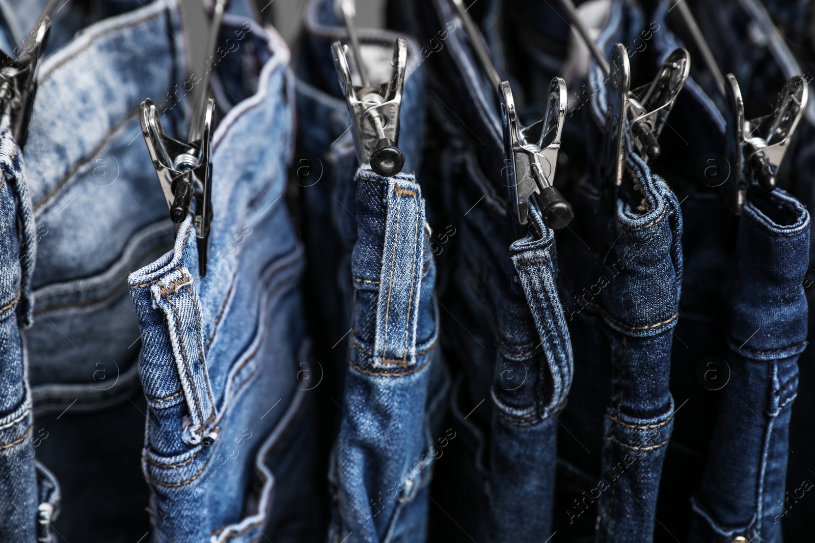 Photo of Metal hangers with different stylish jeans, closeup