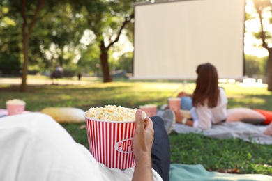 Young man with popcorn watching movie in open air cinema, closeup. Space for text