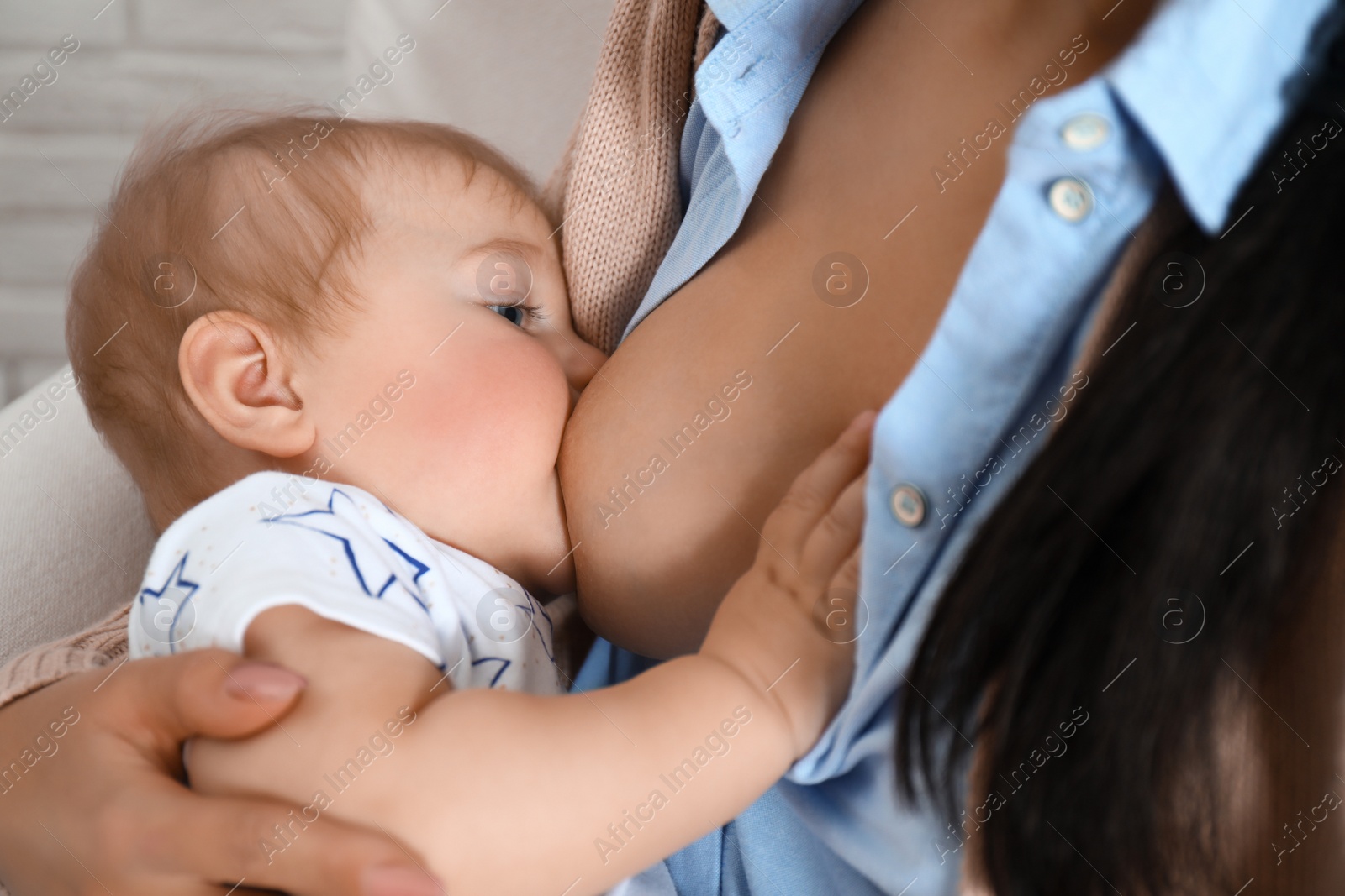 Photo of Woman breast feeding her little baby indoors, closeup