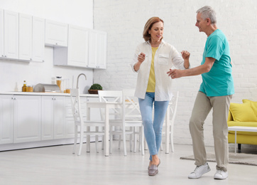 Photo of Happy senior couple dancing in kitchen at home