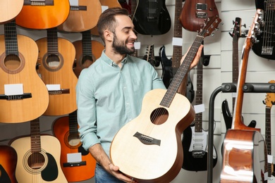 Photo of Buyer choosing guitar in modern music store