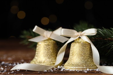 Photo of Bells with bows and artificial snow on table, closeup. Christmas decor