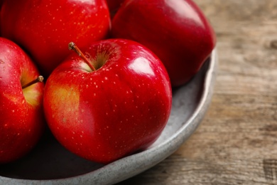 Photo of Plate with ripe red apples on wooden background