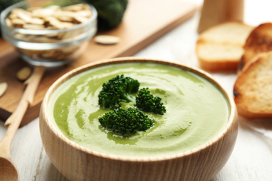 Photo of Delicious broccoli cream soup served on white wooden table, closeup