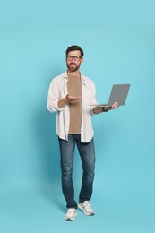 Photo of Handsome man with laptop on light blue background