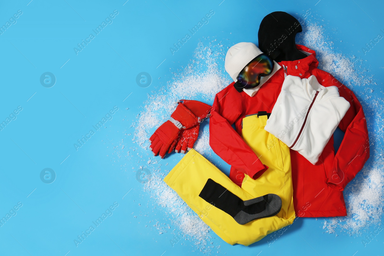 Photo of Stylish winter sport clothes on light blue background, flat lay. Space for text