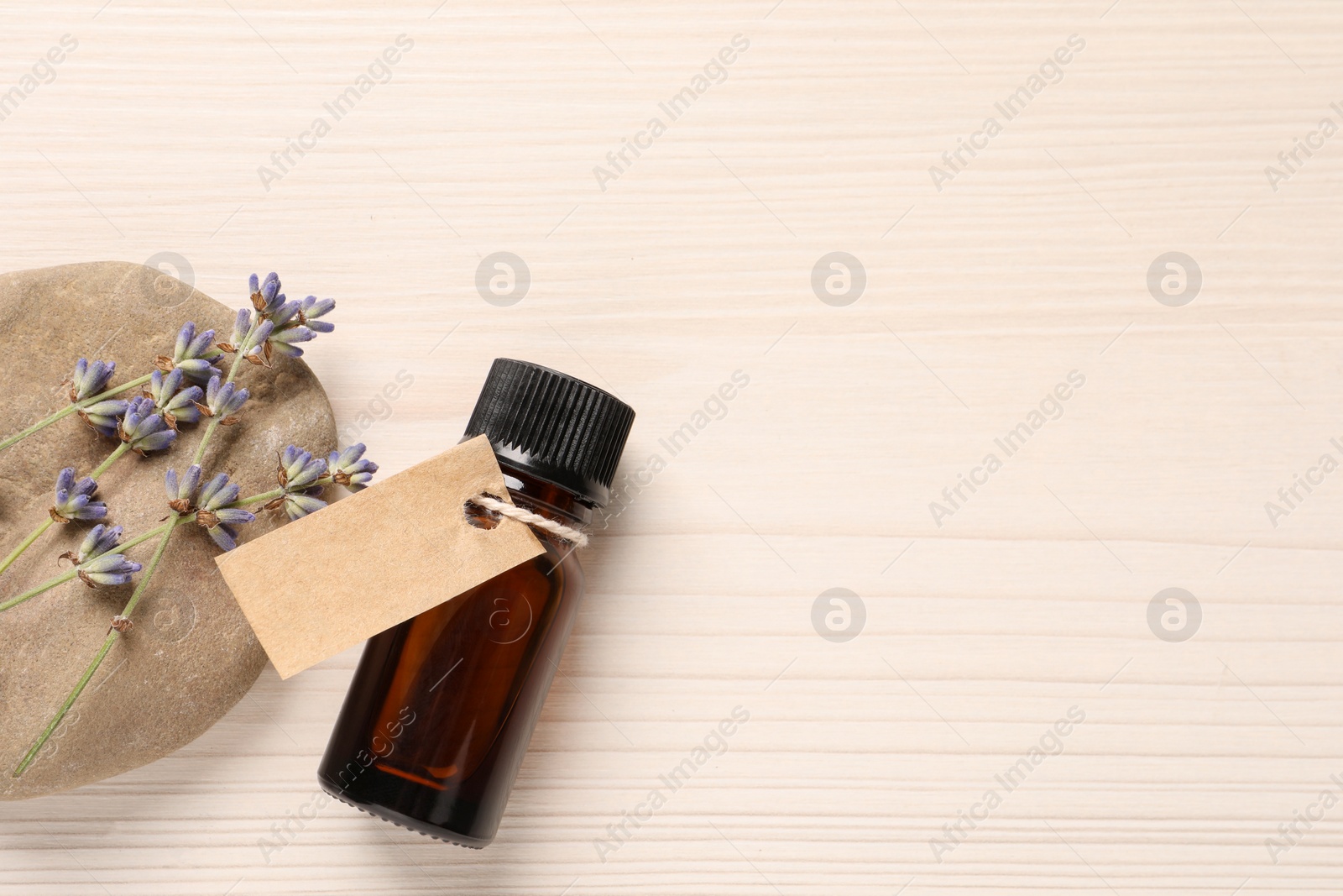 Photo of Bottle of essential oil and lavender flowers on white wooden table, flat lay. Space for text