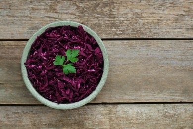 Photo of Tasty red cabbage sauerkraut with parsley on wooden table, top view. Space for text