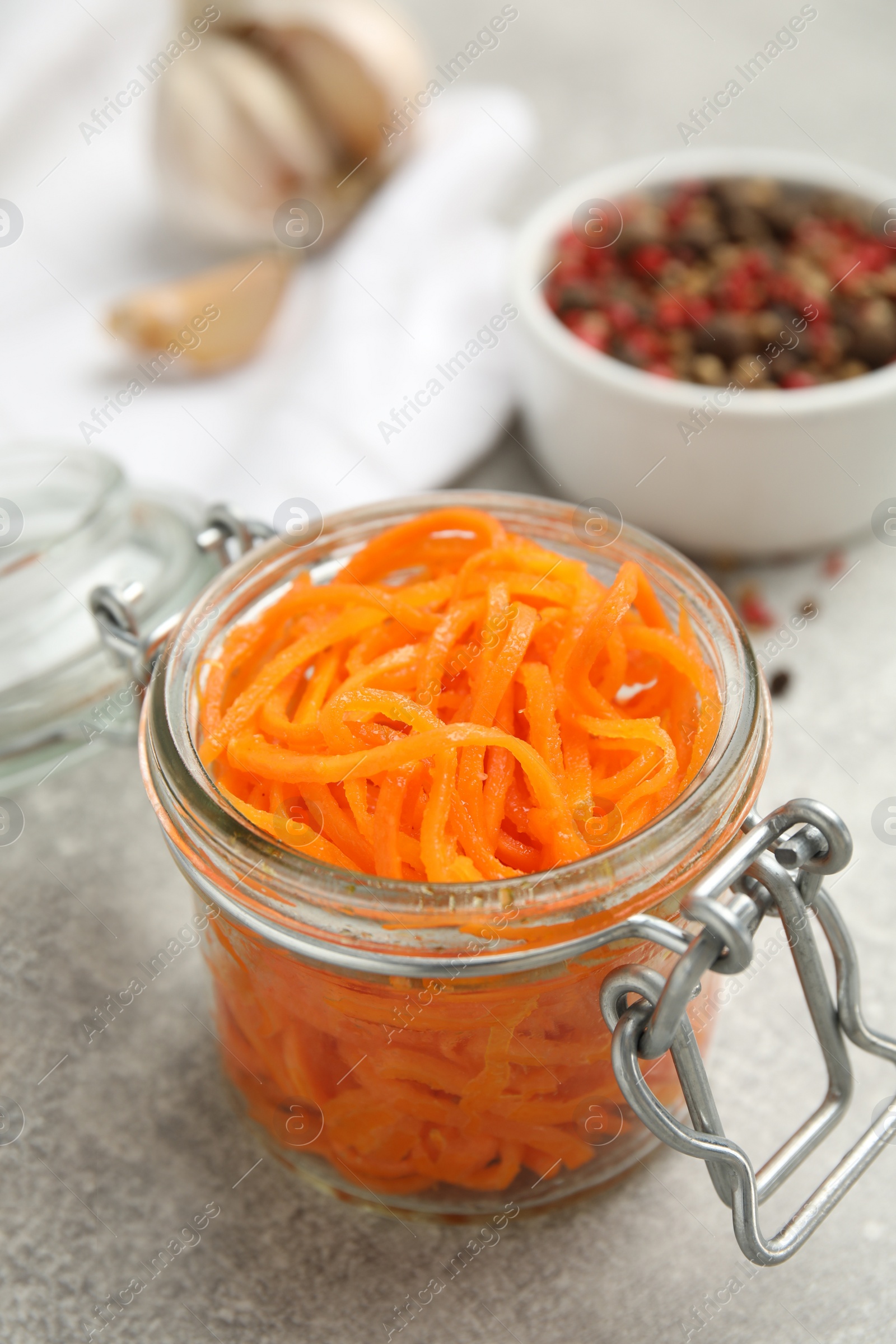 Photo of Delicious Korean carrot salad in glass jar on grey table