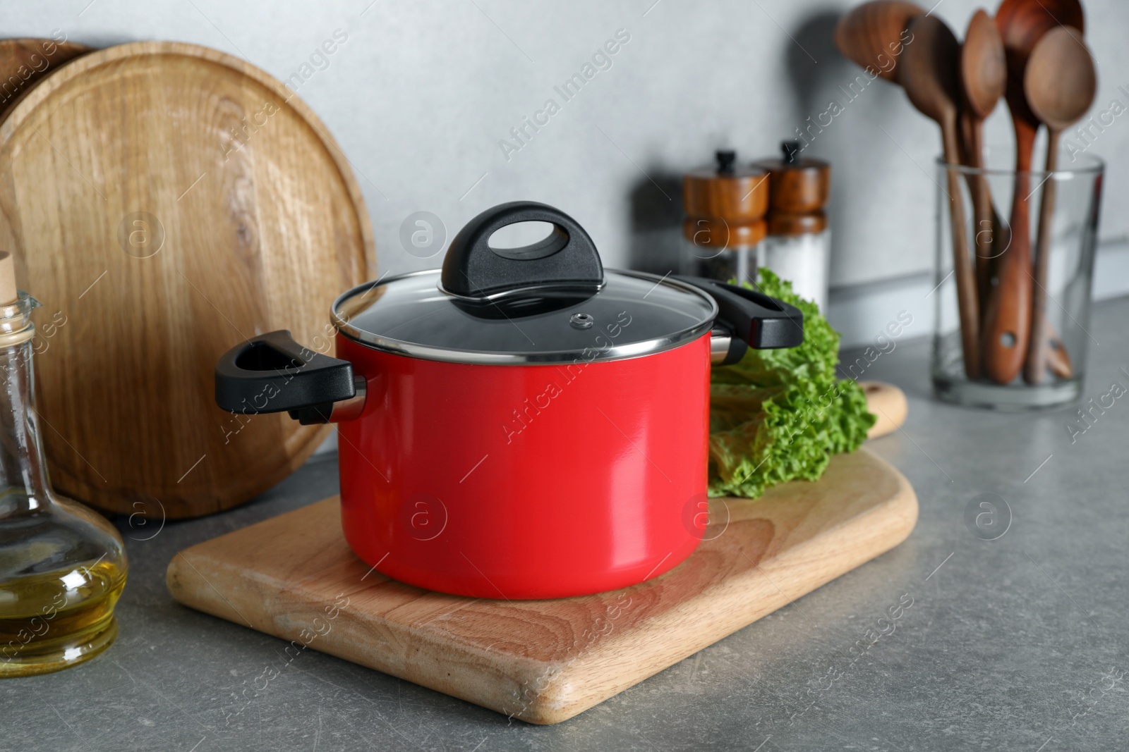 Photo of Pot with lid and other cooking utensils on grey countertop in kitchen