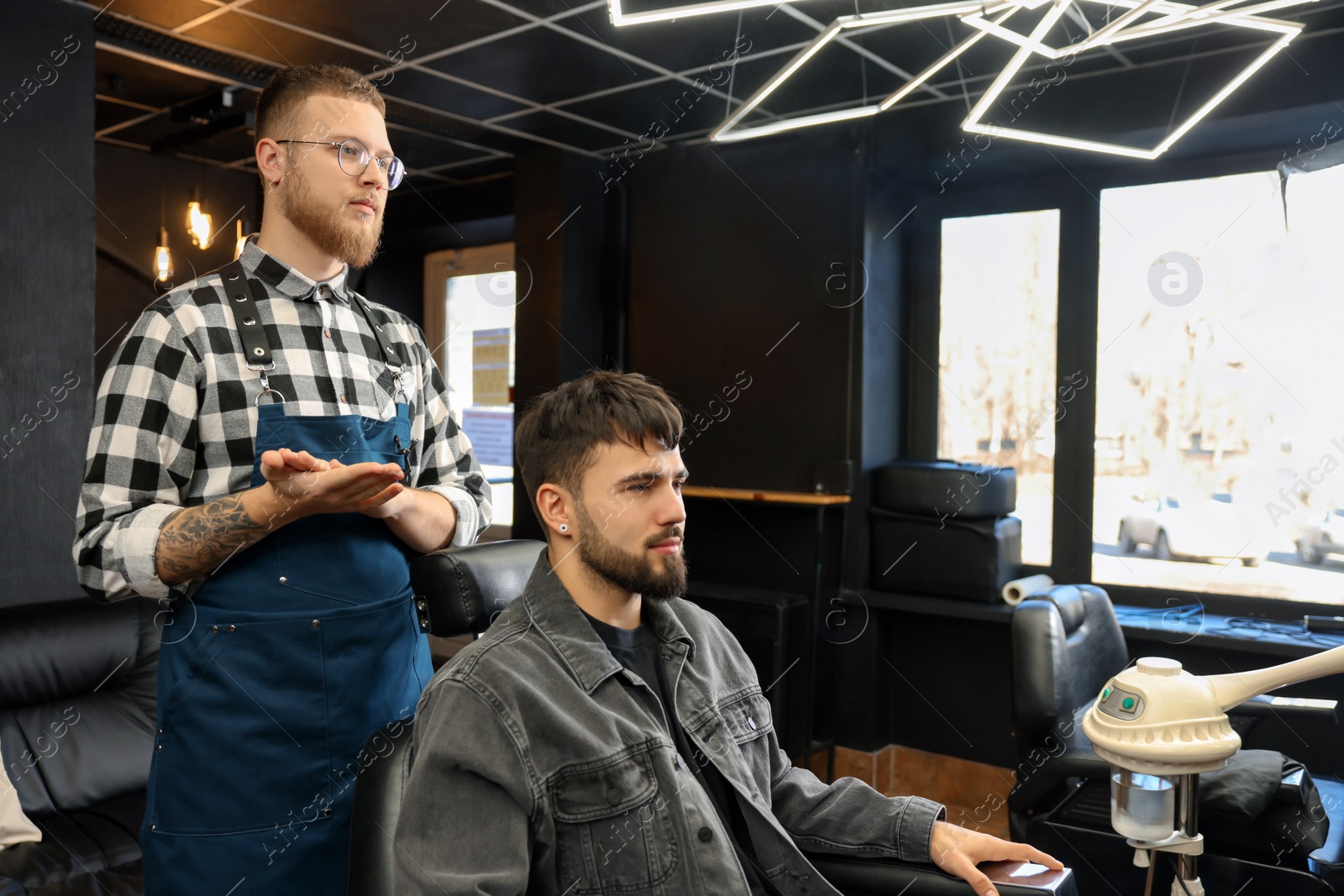 Photo of Professional hairdresser working with bearded client in barbershop