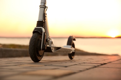 Photo of Modern electric kick scooter outdoors at sunset, closeup