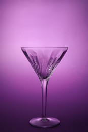 Photo of Elegant empty martini glass on purple background