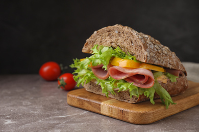 Photo of Tasty sandwich with ham on grey table against black background. Space for text