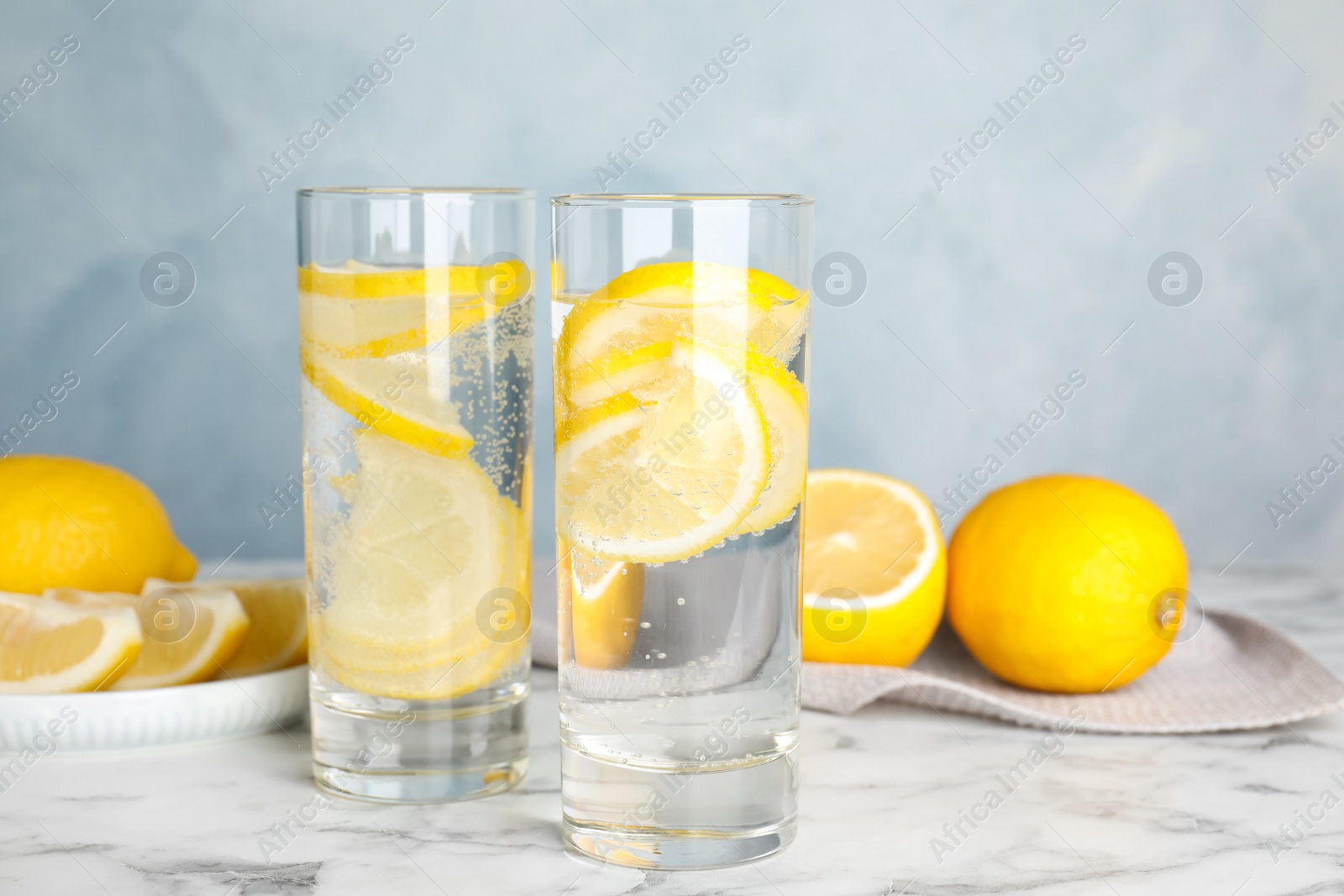 Photo of Soda water with lemon slices on white marble table