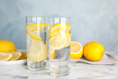 Photo of Soda water with lemon slices on white marble table