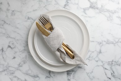 Stylish setting with cutlery, napkin and plates on white marble table, top view