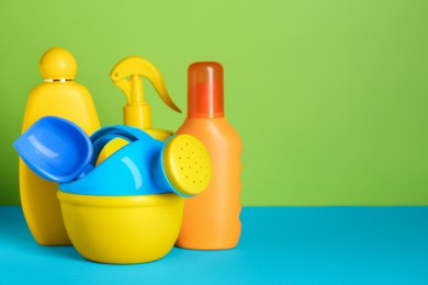 Photo of Different suntan products and plastic beach toys on color background. Space for text