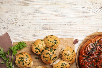 Photo of Traditional Ukrainian bread (Pampushky) with garlic on white wooden table, flat lay. Space for text