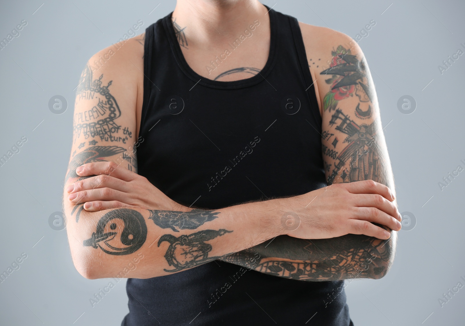 Photo of Young man with stylish tattoos on grey background