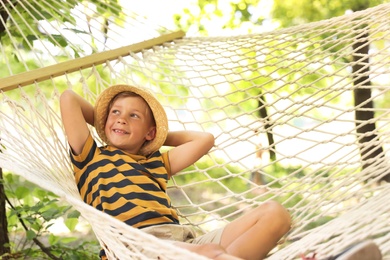 Photo of Little boy resting in hammock outdoors. Summer camp