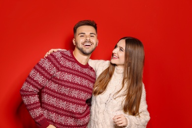 Photo of Couple wearing Christmas sweaters on red background