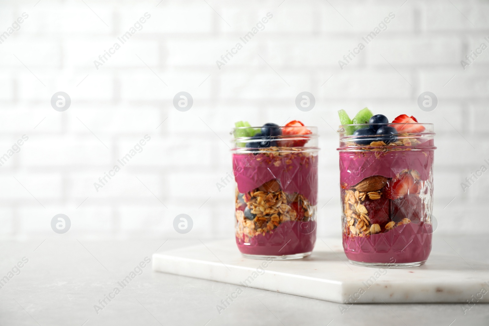 Image of Tasty dessert with acai smoothie, granola and berries on marble table. Space for text